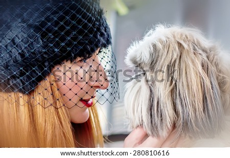 Portraits of beautiful ginger hair woman in hat with veil and cute shaggy shih tzu dog looking at each other
