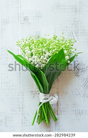 Bunch of beautiful lilies of the valley on the white  rustic wooden floor. Vertical image