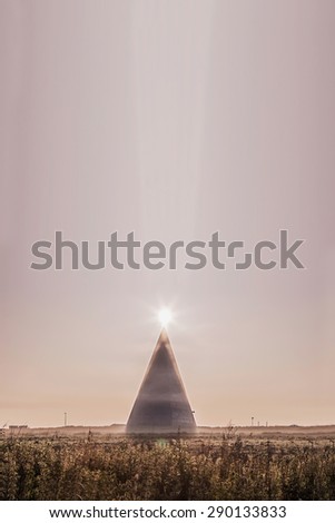 Misty energetic power pyramid with morning sun on the top and a pillar of light in Moscow area, Russia. Image with selective focus and toning