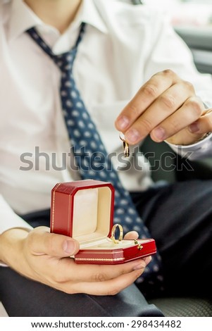 Man is holding pair of wedding rings. One ring is consist of several connected rings. Image with selective focus