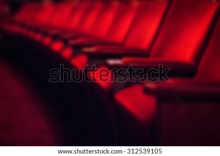 Blurred dark background: row of empty red theater chairs