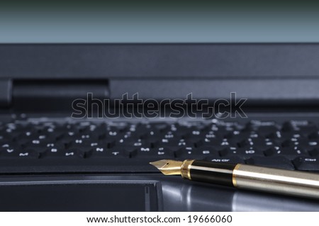 gold feather pen on the keyboard of the personal computer.