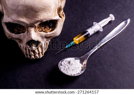 Skull and spray with yellowish liquid. Next to them are a spoon with white powder, which is similar to heroin . Isolated on black