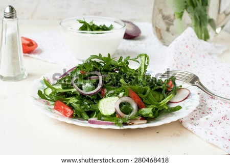 Spring salad with fresh lettuce rukolla, tomato, cucumber, radish, onion kolechekkrasnogo, dill, parsley, seasoned with sunflower oil in a bowl on a white background