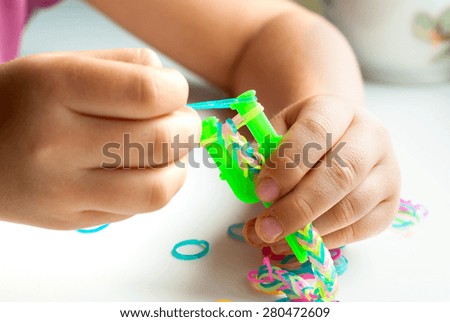 Young girl make rubber band bracelet with a loom