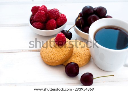 cup of black strong coffee and two biscuits with berries - raspberries and cherries, summer light breakfast