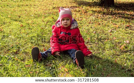 Girl in a red coat walks in autumn park