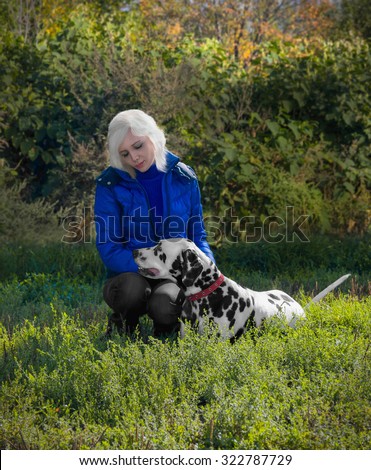 Magnificent Dalmatian dog on the nature of the hunt with a girl in a blue jacket and black jeans torn to mining