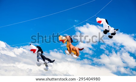 Three dog-like kites flying in the blue sky on the kite festival