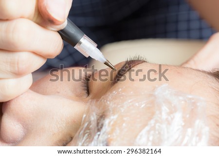 Asia woman applying permanent make up on eyebrows tattoo.