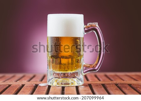 Lager beer in mug with foam and bubbles on wood table