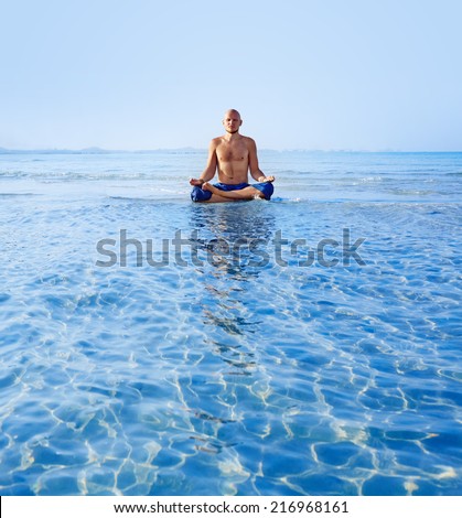 Man meditating upon the ocean at sunrise