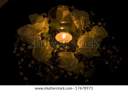 holiday candle burning with white rose around