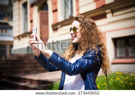 Technology internet and happy people concept - beautiful girl in sunglasses taking picture with smartphone camera, woman using cell phone. Urban style.