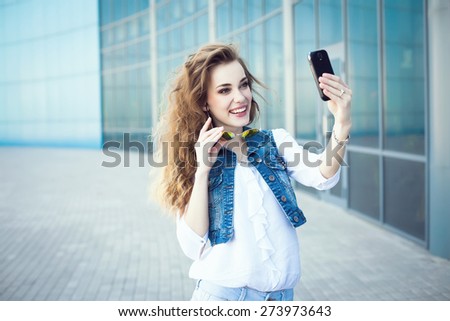Technology internet and happy people concept - beautiful girl taking picture  with smartphone camera, woman using cell phone on blue