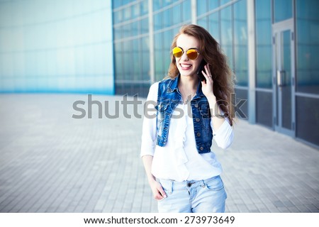 Technology internet and happy people concept - beautiful succesful woman in sunglasses talking on cellphone while walking outdoor. City business woman working.