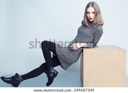 Fashion portrait of young beautiful female model with perfect make up in casual dress and boots.