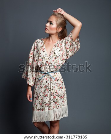 Fashion portrait of beautiful woman in luxurious floral dress posing in studio.