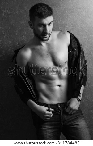 portrait of handsome muscular man at black leather jacket and jeans