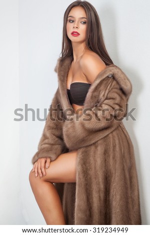Luxury beautiful woman in fur mink coat with vest looking at camera over white background.