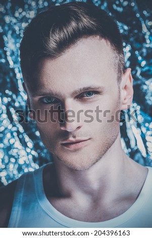 Fashion portrait of handsome man posing over foil background. Close up