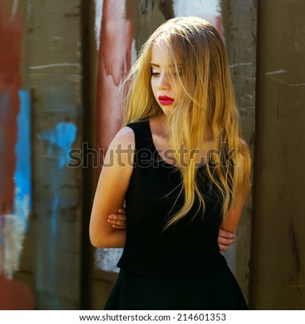 Hipster style. Fashion portrait of beautiful blond-haired girl in trendy black crop top and skirt posing over rusty metal background. Perfect skin and make-up. Outdoor shot