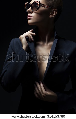 portrait of a beautiful girl posing in studio in black jacket and fashion sunglasses. The concept of stylish and sexy women. perfect skin and body