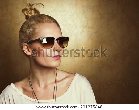 Vintage portrait of young beautiful blonde hipster girl in vintage glasses over golden background. Copy space. Studio shot