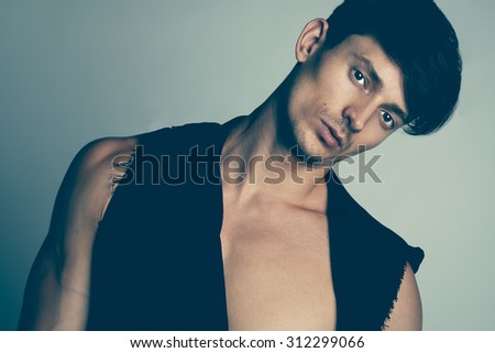 Portrait of hansome male model in black clothes posing over gray background. Close up. Studio shot.