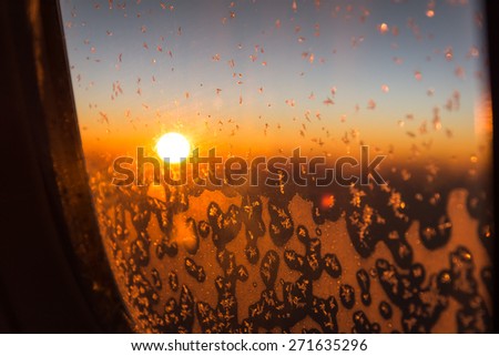 snow on plane window with sun rise background