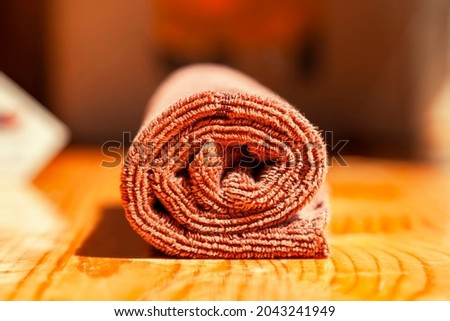 Brown three-ply microfibre tea towel rolled up on a wooden surface Imagine de stoc © 