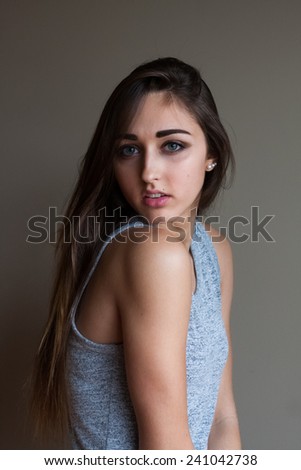 Portrait of gorgeous young woman with long brown hair and blue eyes. Posing in studio, wearing fashionable clothing.  Ombre hair.