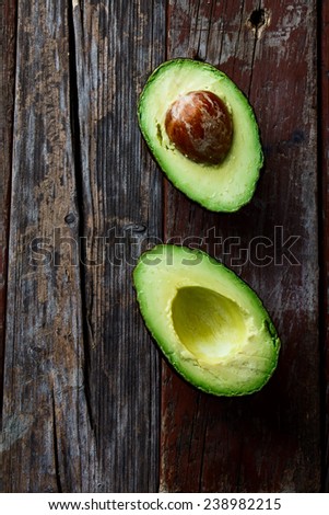 Halved avocados on rustic wooden background. Top view.