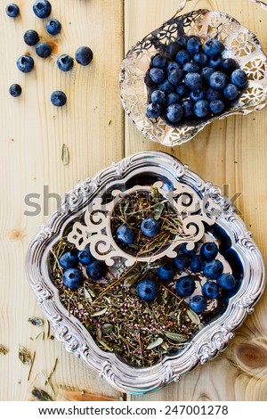Mix of bio herbal tea and fresh blueberry on wooden background. Top view.