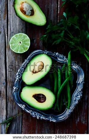 Green halved avocados and beans  on vintage metal plate - healthy food, diet or cooking concept. Top view.