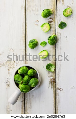 Fresh brussel sprouts over white wooden background. Top view. Healthy food, diet or cooking concept.