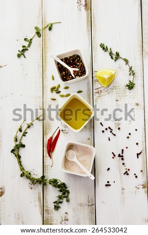 Herbs, spices, olive oil, pink salt and lemons on white wooden board. Food background. Top view.