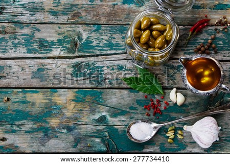 Top view of olives in jar and Olive Oil on rustic wooden table - italian food concept. Background with space for text.