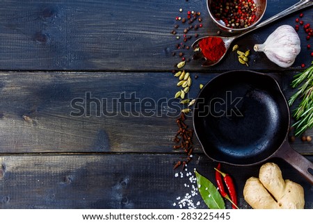 Spices and herbs selection with vintage cast iron skillet on rustic wooden background. Vegetarian food, health or cooking concept.