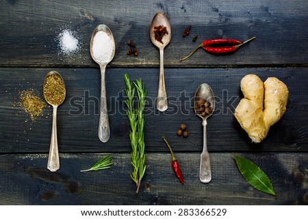 Top view of food elements - herbs and spices, old metal spoons and dark wooden background - cooking, healthy eating.