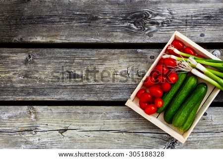 Salad ingredients (tomatoes, green onion and cucumbers) on vintage wooden texture. Space for text. Healthy or vegetarian eating concept.