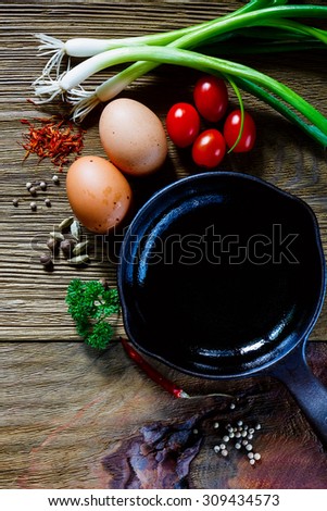 Food background with healthy ingredients and iron pan for cooking over rustic wood. Vegetarian food, health or cooking concept.
