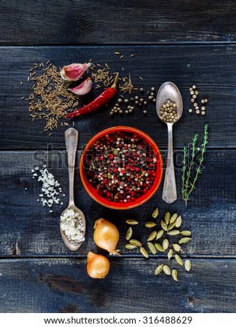 Ceramic bowl with peppercorn mix, herbs and spices selection over dark old wooden background. Food or cooking concept