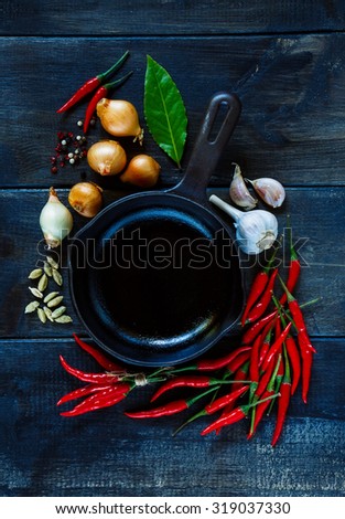 Hot red peppers, garlic, onion with spices and herbs for use as cooking ingredients on dark wooden background. Vegetarian food, health or cooking concept.
