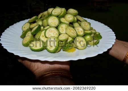Female holding plate of Spiny gourd vegetable also known as Spine gourds or Kantola are seasonal healthy vegetables grown in India Asia, Cut in to slices ready to prepare spiney gourd curry Photo stock © 