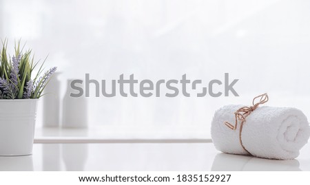 Roll of white spa towel tied with hemp rope on white counter table, copy space.