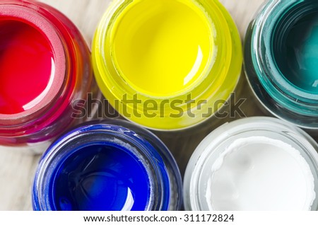 Top view of opened bottles of color on wooden background.