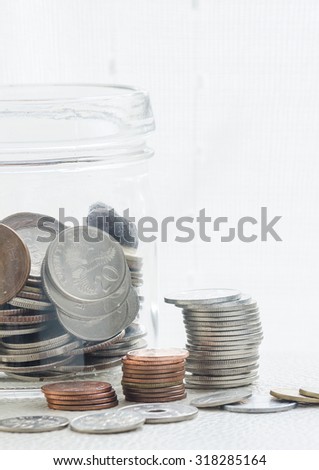 coins stacked and coins in the bottle on white background,soft focus.