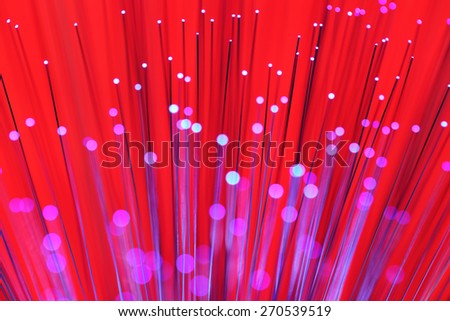 Medium to light magenta lights shooting upward with purple trails against a bright red background. The foreground lights are out of focus, leaving a translucent orb of light at each source.
