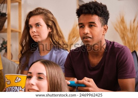 Similar – Image, Stock Photo Friends playing video game at home. Gamers playing online in dark room lit by neon lights. Competition and having fun